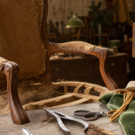 Rénovation fauteuil Voltaire : garnissage et outils de tapissier sur fauteuil ancien